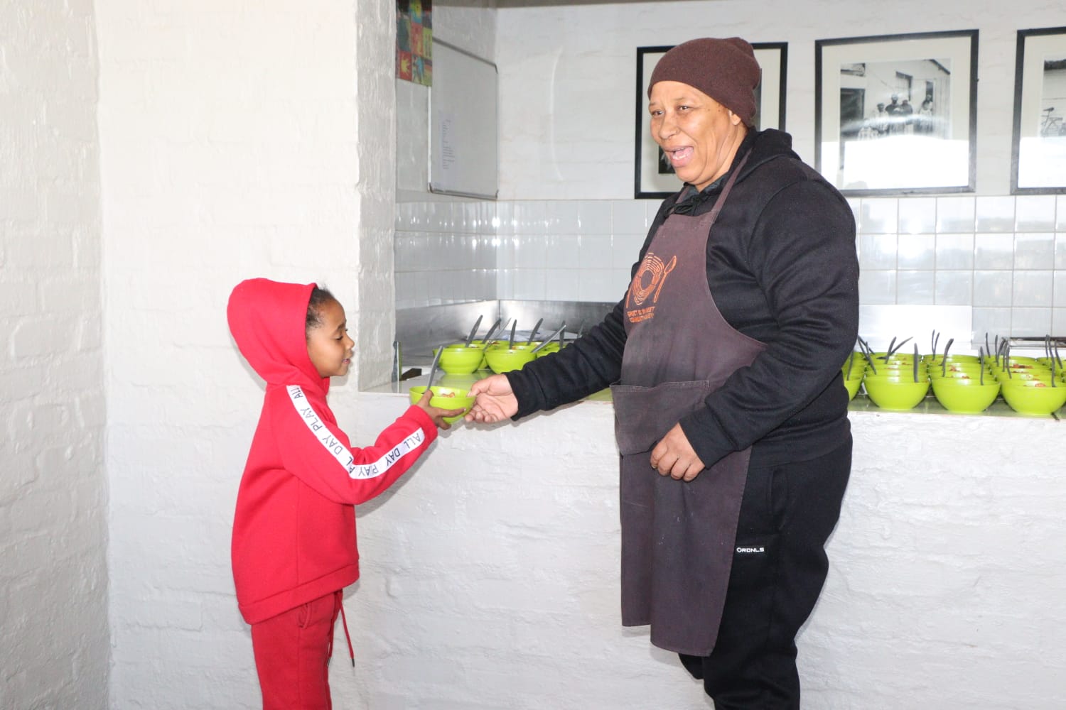 Aunt Landi handing a bowl of food to a child