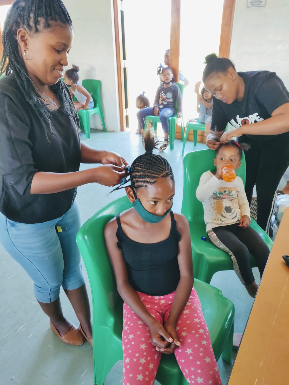Girls having their hair braided at the hair styling station