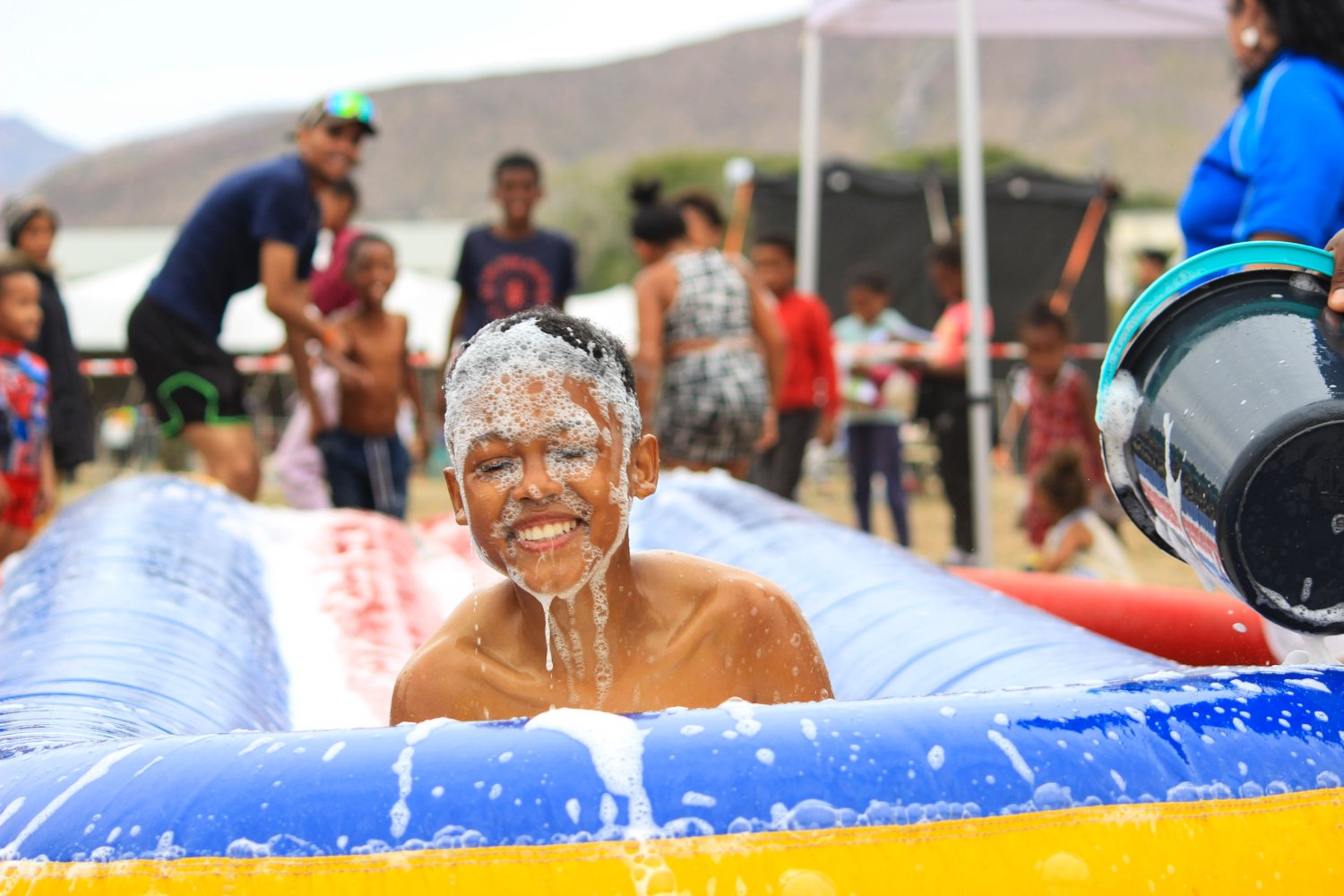 A child enjoying a foam slide at a PACT community event