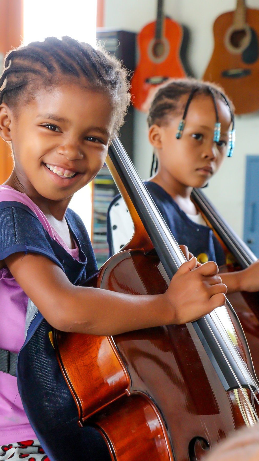 Two young children learning cello at the ARCO-PACT Strings project