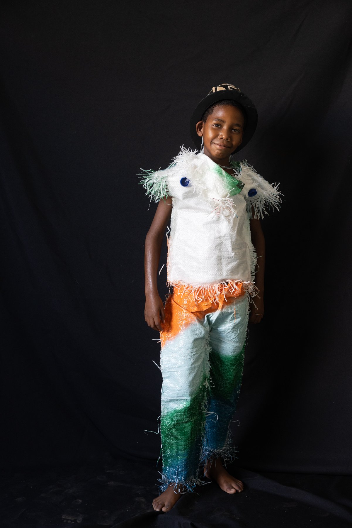 A child modelling a recycled-material outfit against a black backdrop