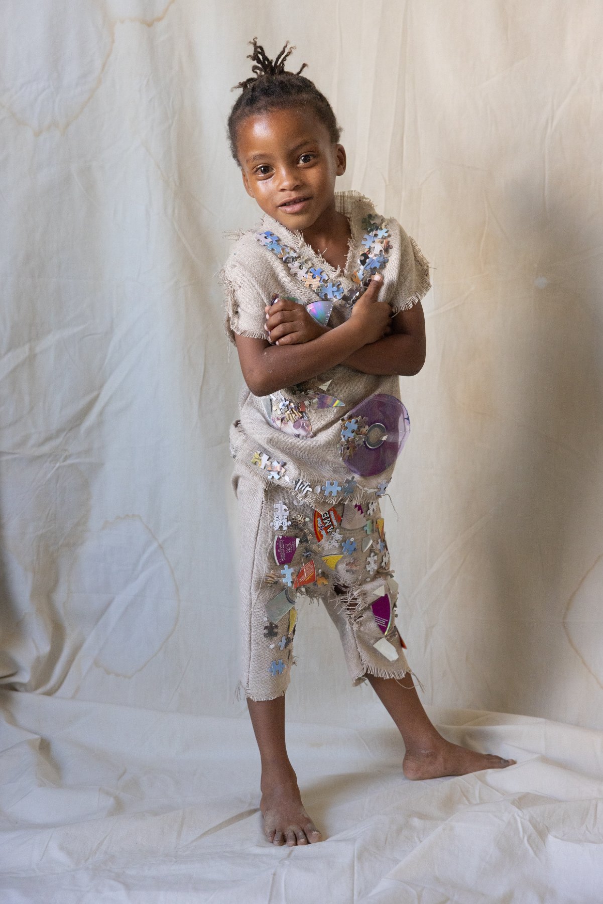 A young girl in a bubble-wrap couture skirt against a black backdrop