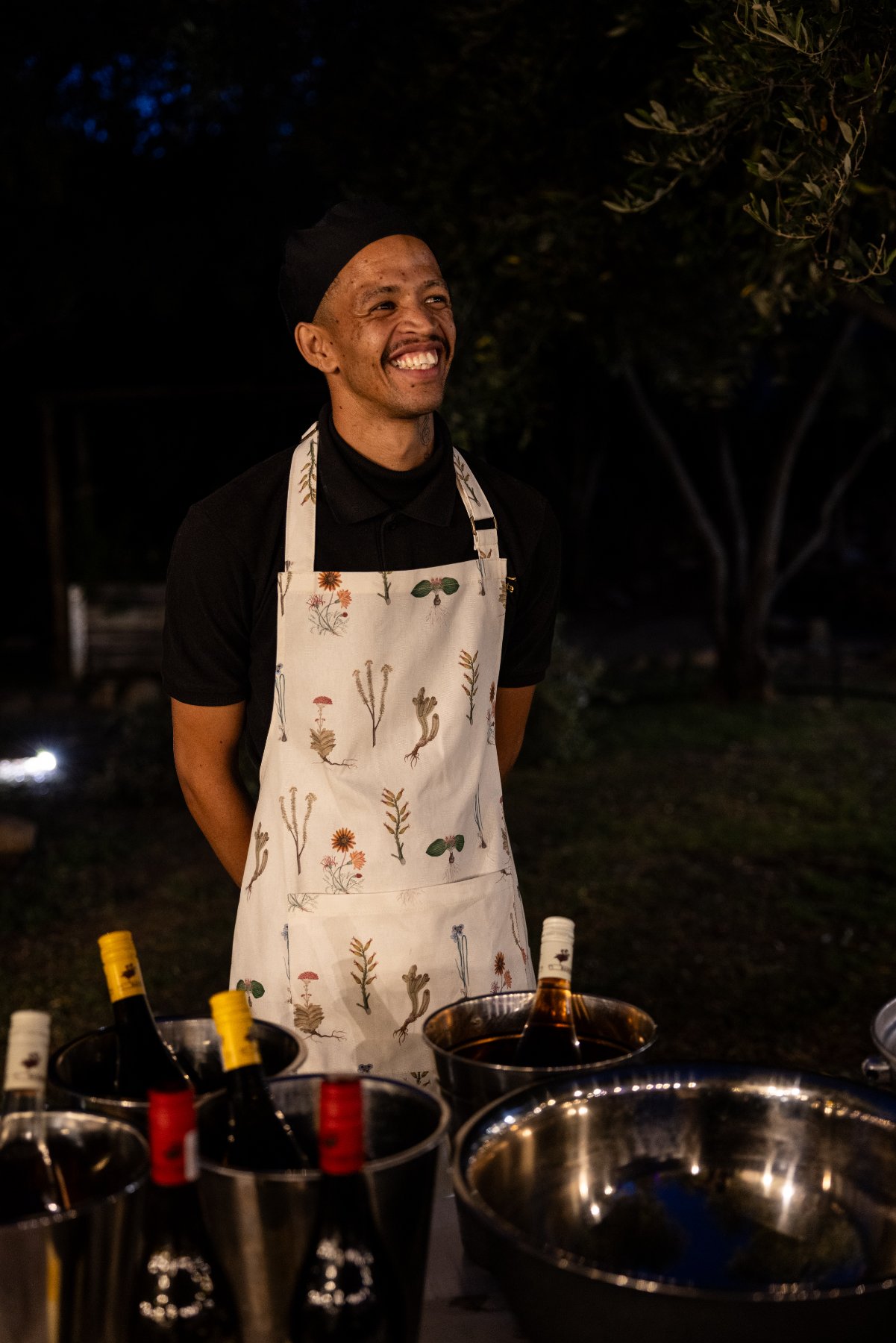 An ONS hospitality student hosting at an evening event, in a botanical-print apron