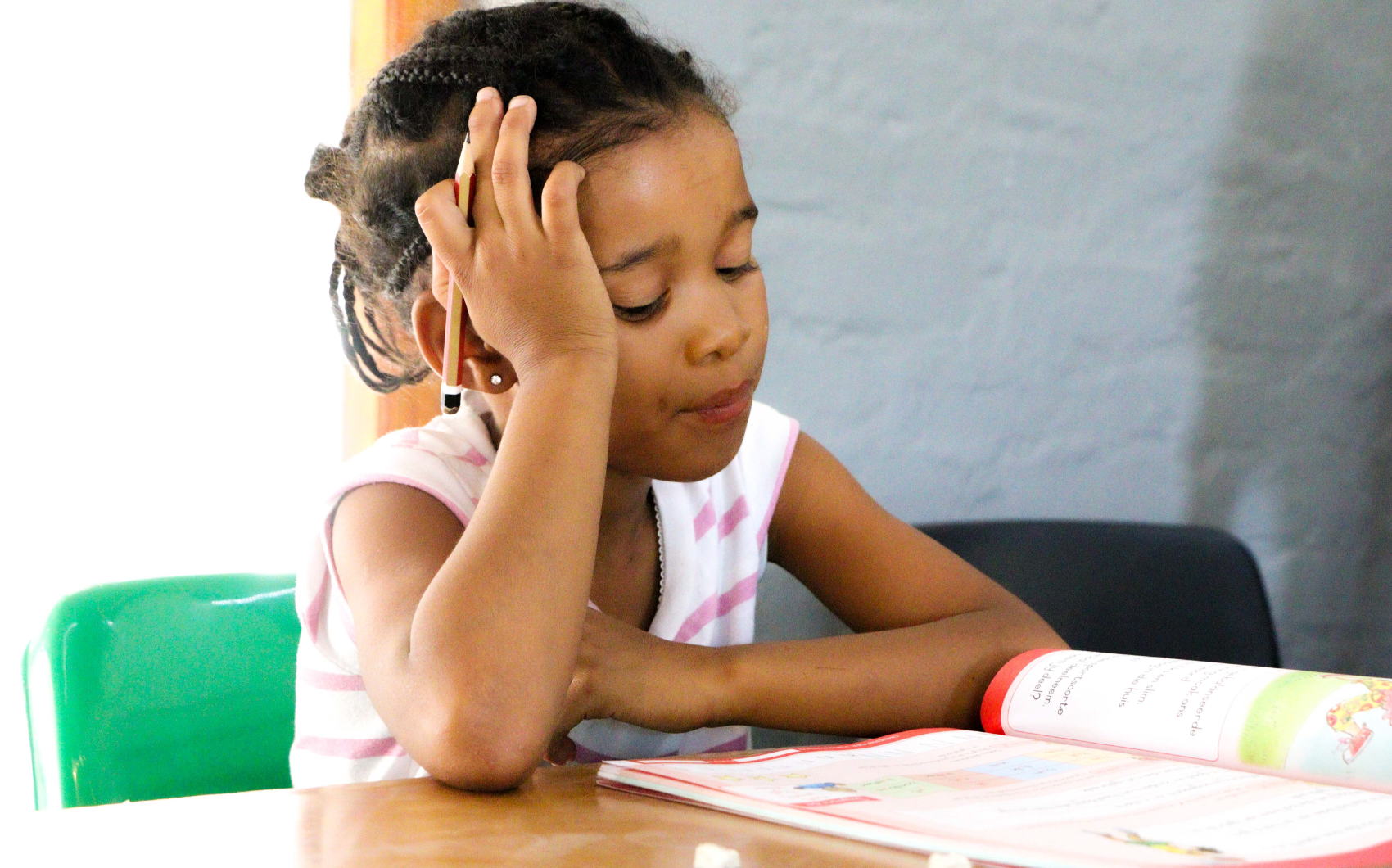 A young learner concentrating on her homework at the Centre