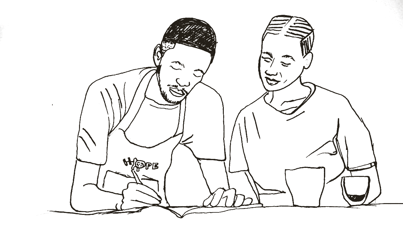 Two people at the Hope Warrior Coffee Bar, writing together over coffee