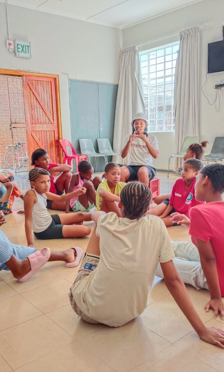 Children painting together on the floor at the Leeu-Gamka Centre
