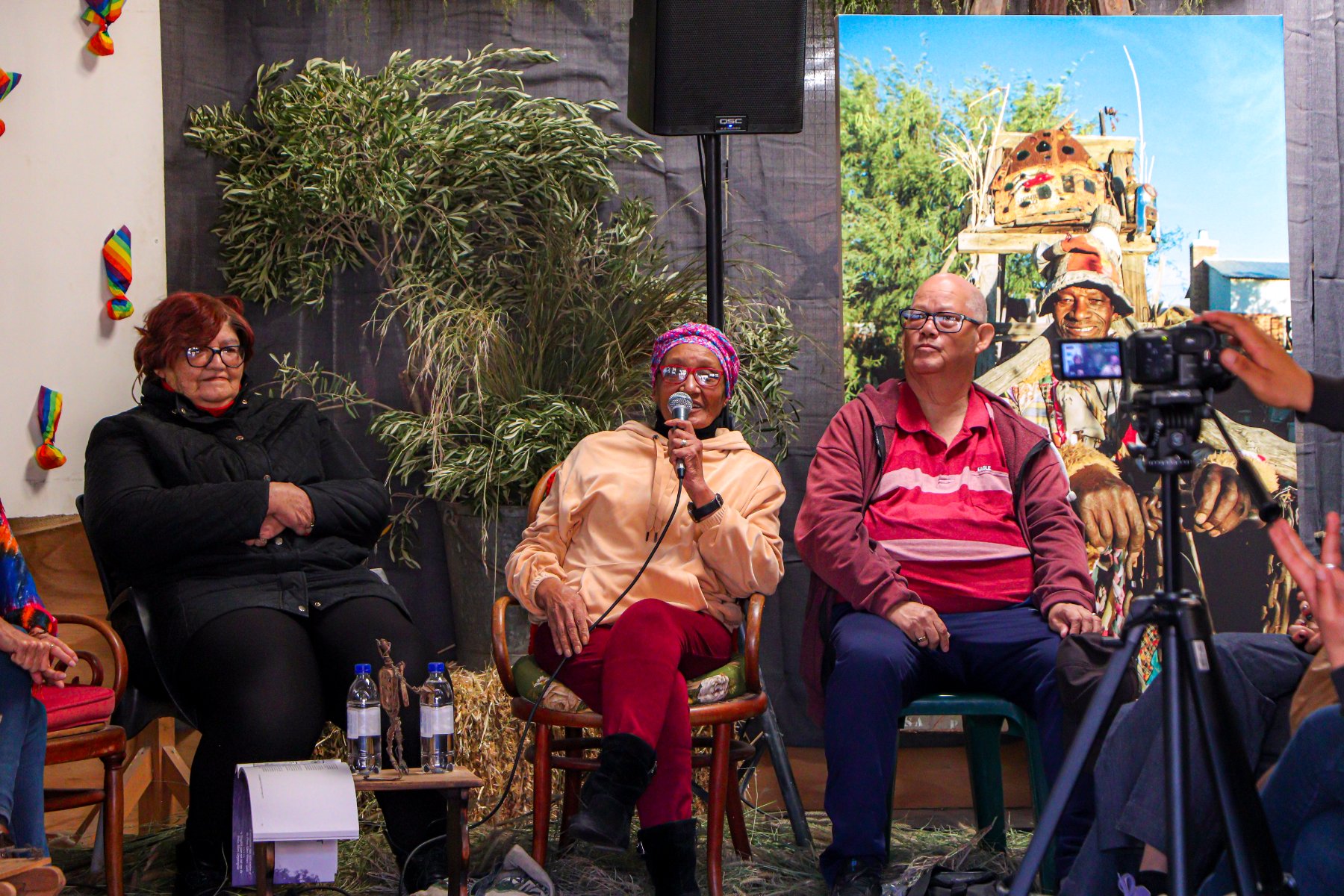 Storytellers sharing Stoepstories at a Museum Services heritage activation, with an Outa Lappies portrait behind them