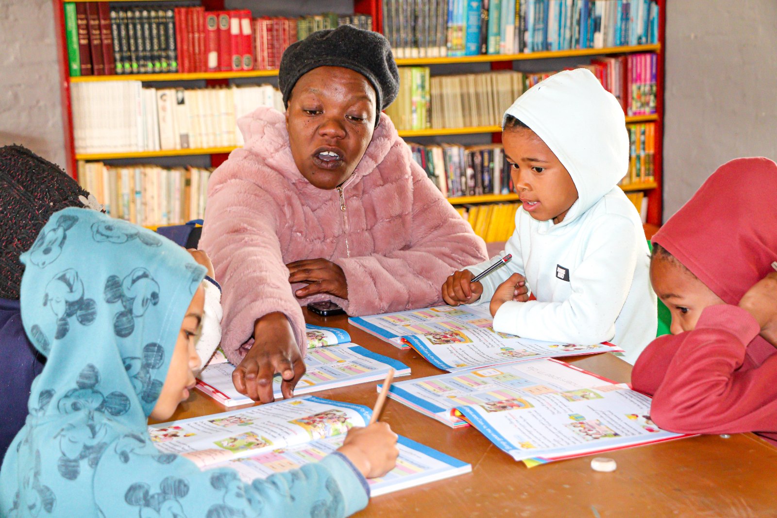 A facilitator counting with a child on a red bead abacus