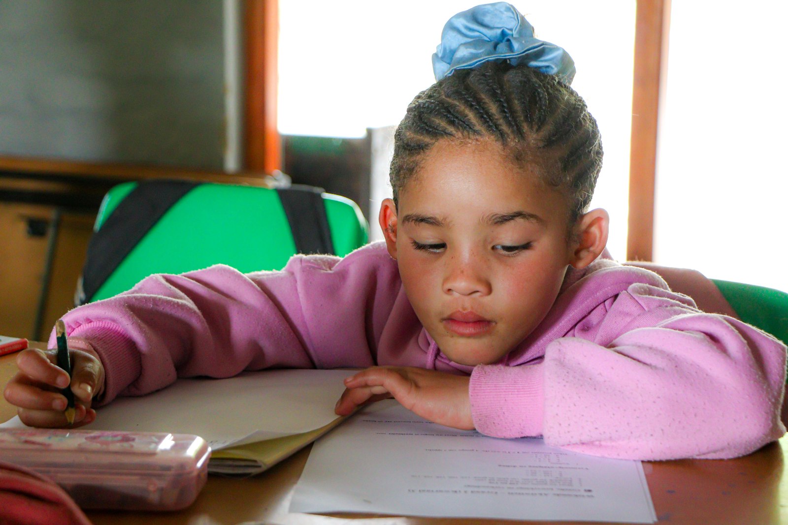 A facilitator working through workbooks with four children in the library